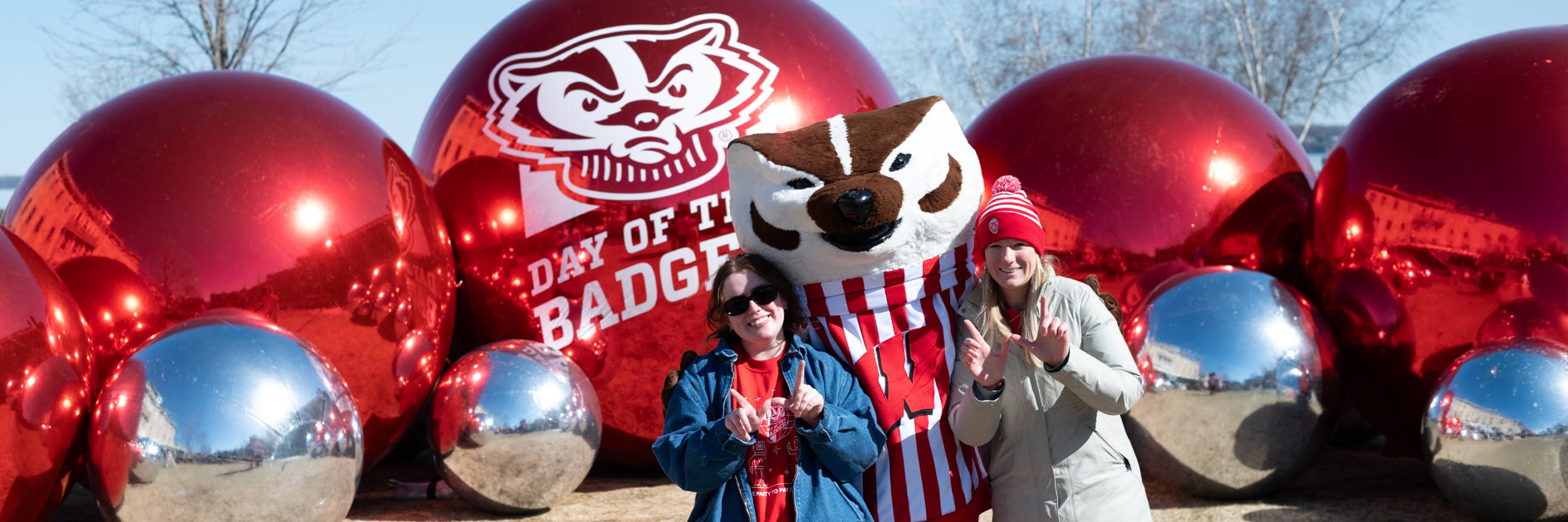 Bucky Badger pictured with two fans in front of shiny decorations